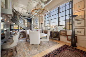 Dining space featuring a towering ceiling, wood finished floors, a chandelier, and stairway