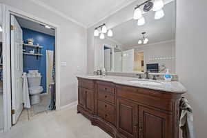 Full bathroom with crown molding, toilet, double vanity, baseboards, and a shower with shower curtain