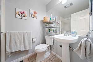 Full bath featuring toilet, a shower stall, tile patterned floors, and baseboards