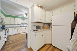 Kitchen with stainless steel appliances, wood finished floors, a ceiling fan, ornamental molding, and light countertops