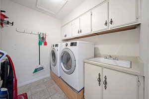 Washroom with separate washer and dryer, cabinet space, attic access, and baseboards