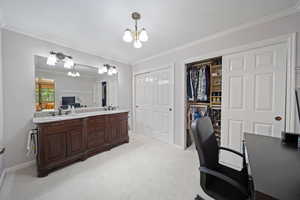 Office area with a sink, a chandelier, ornamental molding, light colored carpet, and baseboards