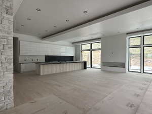 Kitchen with open floor plan, white cabinetry, a large island, light wood finished floors, and modern cabinets