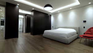 Bedroom with a tray ceiling, light wood-style floors, and recessed lighting