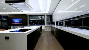 Kitchen featuring a sink, modern cabinets, light wood-style floors, dark cabinetry, and a spacious island