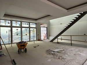 Unfurnished living room with a tray ceiling, healthy amount of natural light, and stairway