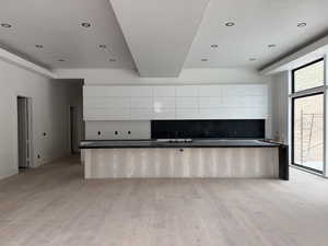 Kitchen featuring backsplash, white cabinets, dark countertops, modern cabinets, and recessed lighting