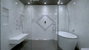 Full bath with a marble finish shower and a freestanding tub