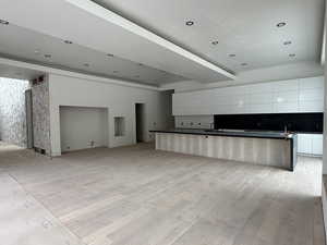 Kitchen with modern cabinets, open floor plan, a spacious island, white cabinetry, and dark countertops