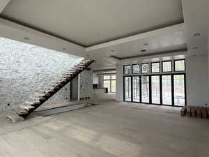 Unfurnished living room with a tray ceiling, light wood-type flooring, and recessed lighting