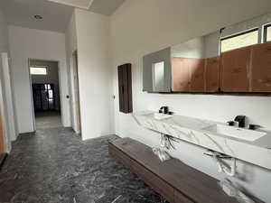 Full bath with plenty of natural light, stone flooring, and double vanity