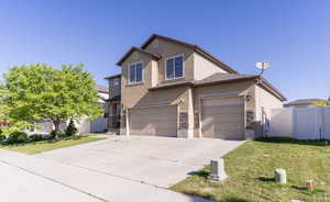 Traditional-style home featuring stone siding, driveway, stucco siding, and a garage
