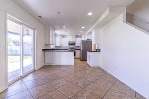 Kitchen with appliances with stainless steel finishes, dark countertops, a sink, white cabinetry, and recessed lighting