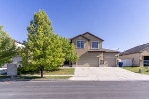 Traditional-style house featuring stucco siding, driveway, a garage, and fence
