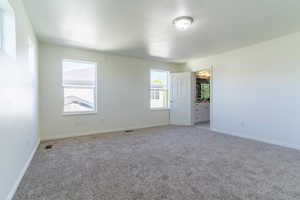 Empty room featuring light colored carpet, baseboards, and a textured ceiling