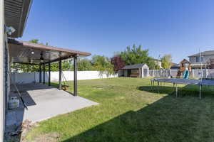 View of yard with a trampoline, a shed, a patio, an outdoor structure, and a ceiling fan