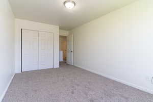 Unfurnished bedroom featuring carpet, a closet, and baseboards