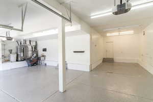 Garage with a garage door opener, gas water heater, and heating unit