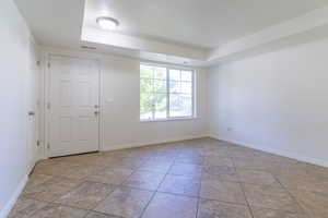 Unfurnished room featuring a tray ceiling and baseboards