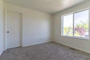 Unfurnished room featuring carpet flooring, healthy amount of natural light, and baseboards