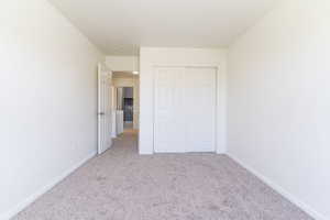 Unfurnished bedroom featuring carpet flooring, baseboards, and a closet