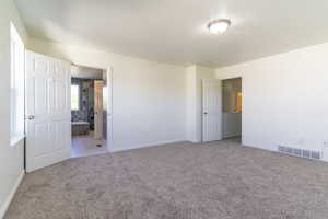 Unfurnished bedroom with carpet flooring, baseboards, and connected bathroom
