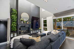 Living room featuring a towering ceiling, a glass covered fireplace, and baseboards
