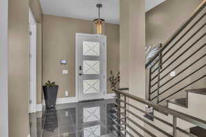 Foyer entrance featuring baseboards, granite tiled floors, and stairs