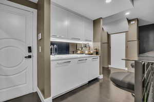 Kitchen with a sink, recessed lighting, light countertops, white cabinetry, and modern cabinets