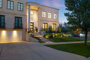 View of front of property featuring driveway, a front lawn, french doors, a garage, and stucco siding