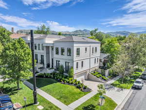 View of front facade with a garage, a mountain view, concrete driveway, stucco siding, and a front lawn