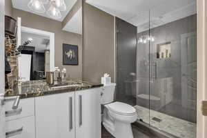 Bathroom with toilet, a shower stall, vanity, and tile patterned floors