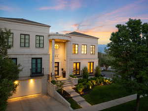 View of front of house with french doors, a garage, driveway, stucco siding, and a yard
