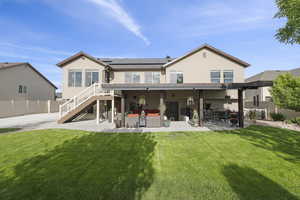 Back of house featuring an outdoor living space, a patio, solar panels and fully landscaped yard