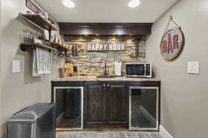 Indoor wet bar featuring wine coolers & stainless steel microwave