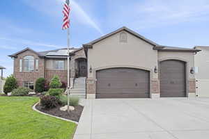 View of front of property with an attached garage, solar panels