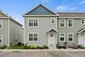 Multi unit property featuring central air condition unit, a shingled roof, and uncovered parking