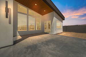 Back of house at dusk featuring fence, a patio, and stucco siding