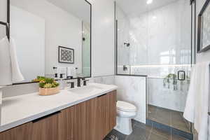 Full bathroom with a marble finish shower, toilet, vanity, tile walls, and recessed lighting