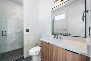 Bathroom with a stall shower, toilet, vanity, tile patterned flooring, and tile walls