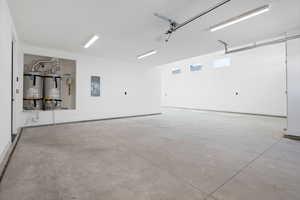 Garage with secured water heater, electric panel, and baseboards