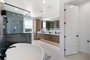 Full bathroom featuring a shower stall, double vanity, recessed lighting, a freestanding bath, and baseboards