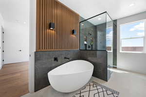 Full bathroom with walk in shower, a freestanding bath, tile walls, and recessed lighting