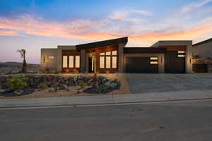 Contemporary house with an attached garage, concrete driveway, stucco siding, and stone siding