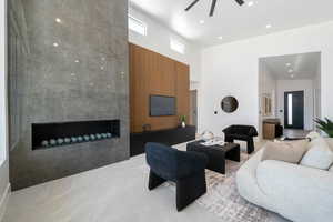 Living area with ceiling fan, a high ceiling, recessed lighting, and a premium fireplace