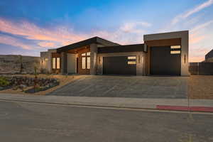 Contemporary house with a garage, concrete driveway, stone siding, and stucco siding