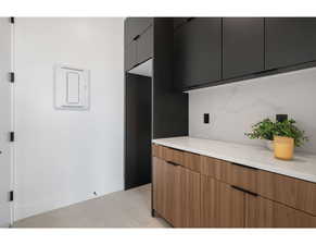 Kitchen with modern cabinets, backsplash, baseboards, and light tile patterned flooring