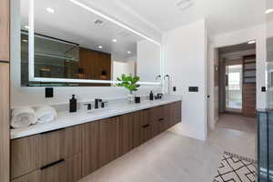 Bathroom with double vanity, baseboards, recessed lighting, and a shower with shower door