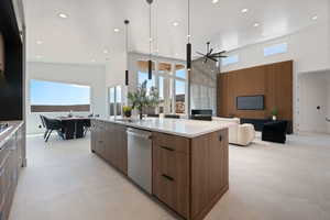 Kitchen with modern cabinets, a sink, a towering ceiling, dishwasher, and a spacious island