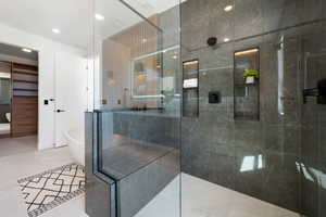 Bathroom with a freestanding bath, a walk in shower, and recessed lighting